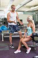 Male trainer talking to fit woman at gym