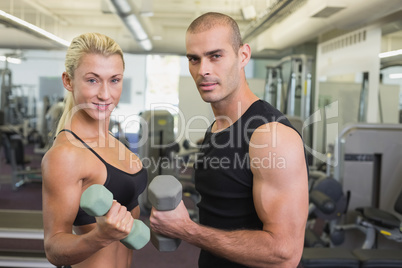 Couple exercising with dumbbells in gym