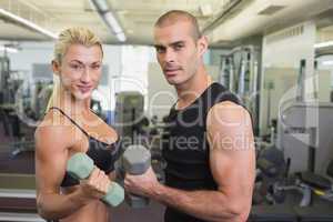 Couple exercising with dumbbells in gym