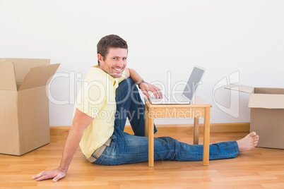Casual man sitting on floor using laptop on the coffee table at
