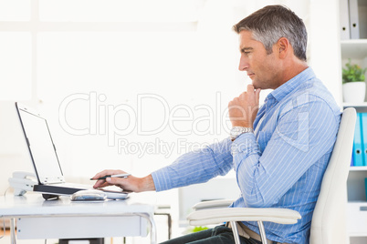 Man in shirt using laptop and thinking