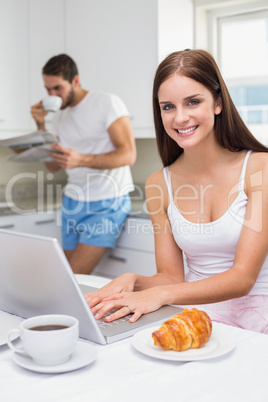 Young woman using laptop at breakfast