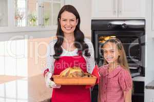 Surprised mother and daughter posing with roast turkey