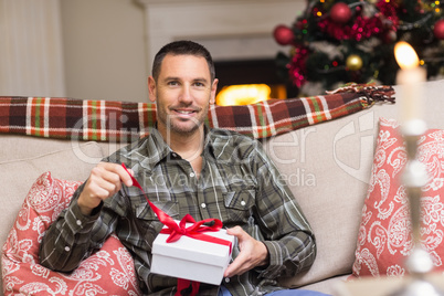 Smiling man opening a gift on christmas day