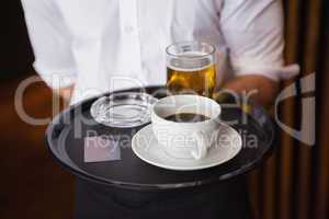 Waiter holding tray with coffee cup and pint of beer