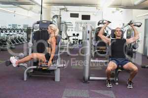 Fit couple using fitness machines at gym