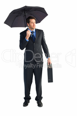 Businessman under umbrella while holding a briefcase