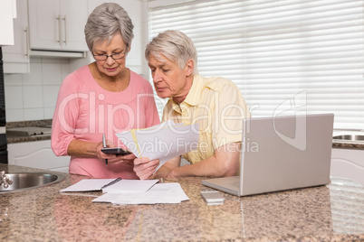 Senior couple paying their bills with laptop