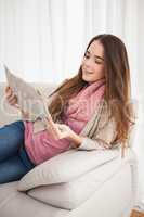 Pretty brunette reading newspaper on couch