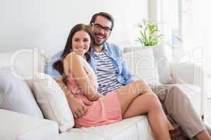 Young couple smiling at camera on couch