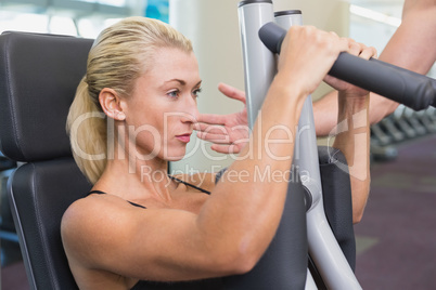 Fit young woman using fitness machine at gym
