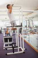 Fit man doing pull ups in fitness studio