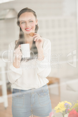 Pretty brunette holding a mug and cookie