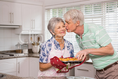 Senior man giving his wife a kiss while taking muffin