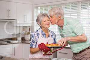 Senior man giving his wife a kiss while taking muffin