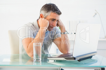 Tired man sitting and looking his laptop