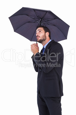 Businesswoman in suit holding umbrella while looking up