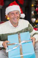 Smiling man in santa hat opening a gift