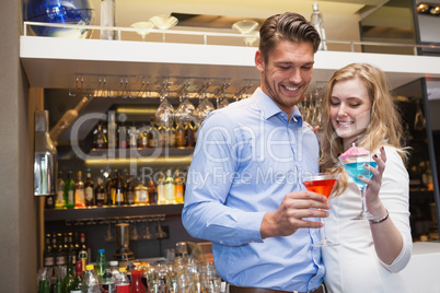 Cute couple standing and drinking cocktails
