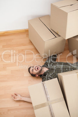 Man lying under fallen boxes