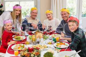 Grandfather in party hat carving chicken during dinner
