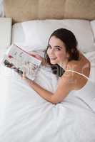 Pretty brunette reading magazine on bed