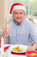Smiling mature man in santa hat toasting with white wine