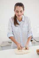 Pretty brunette kneading dough on counter