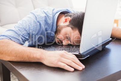 Man sleeping with head resting on laptop keyboard