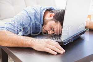 Man sleeping with head resting on laptop keyboard