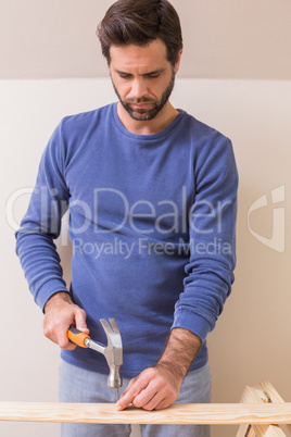 Casual man hammering nail in plank