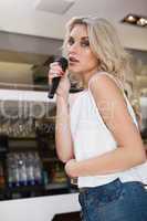 Pretty blonde woman holding a micro while singing
