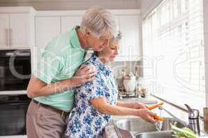 Senior couple washing vegetables at sink