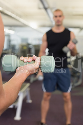 Blurred man exercising with dumbbell in gym