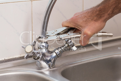 Man fixing tap with pliers