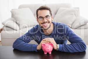 Smiling young man with piggy bank