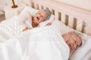 Senior man blocking out his wifes snoring