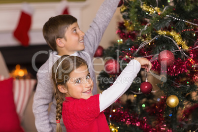 Brother and sister decorating the christmas tree together