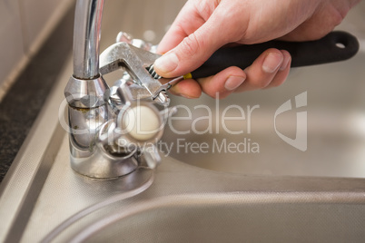 Man fixing tap with pliers