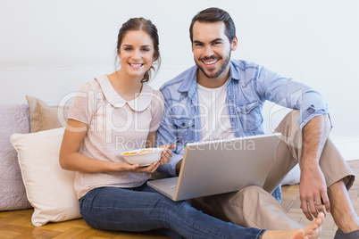 Cute couple sitting on floor using laptop