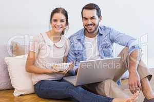 Cute couple sitting on floor using laptop