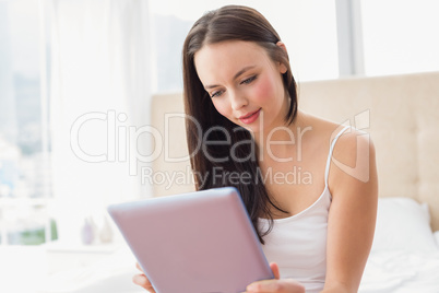 Pretty brunette using tablet pc on bed