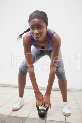 Fit woman lifting up kettlebell