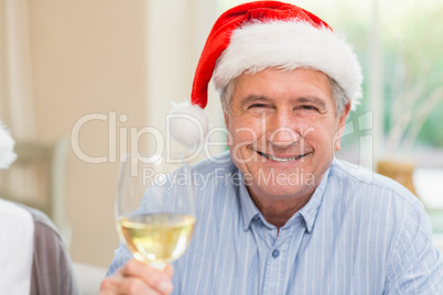 Smiling mature man in santa hat toasting with white wine