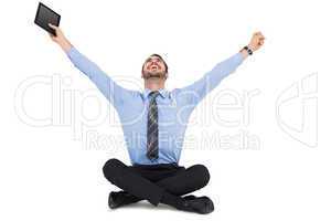 Businessman cheering and holding his tablet