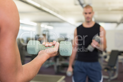 Blurred man exercising with dumbbell in gym