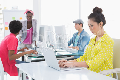 Young creative woman using laptop at desk