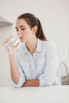 Pretty brunette drinking glass of water