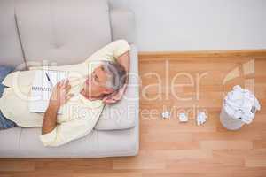 Man lying on couch with crumpled papers