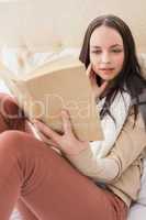 Pretty brunette reading on her bed